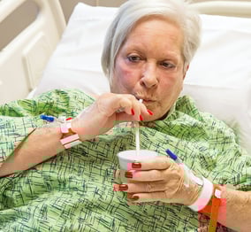 A woman in a hospital bed drinking from a straw