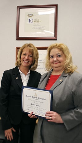 President's E Star Award on wall. Martha Flannery and Amy Bosco showing award certificate from the state senator.