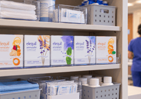 five boxes of Elequil Aromatabs on a shelf in a medical cabinet with a nurse in the background