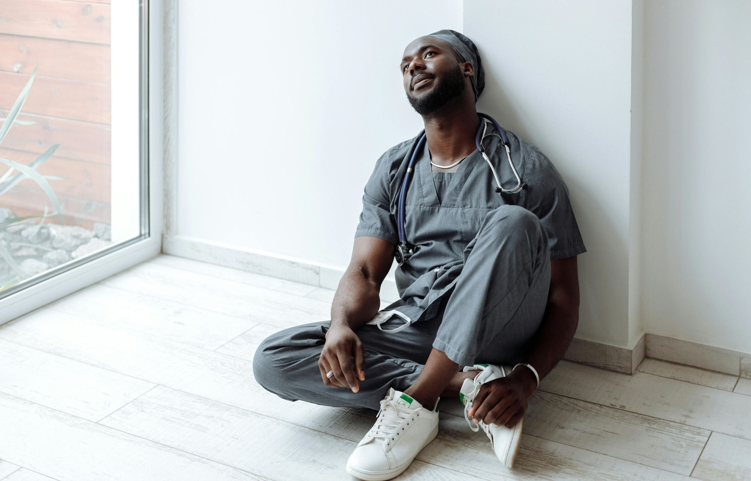 A nurse sitting on the floor, visibly stressed and tired.