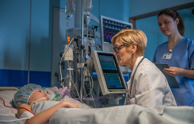 A doctor and nurse talking to a patient in the ICU.