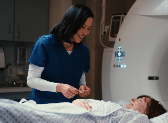 A technologist talking with a patient on a CT machine
