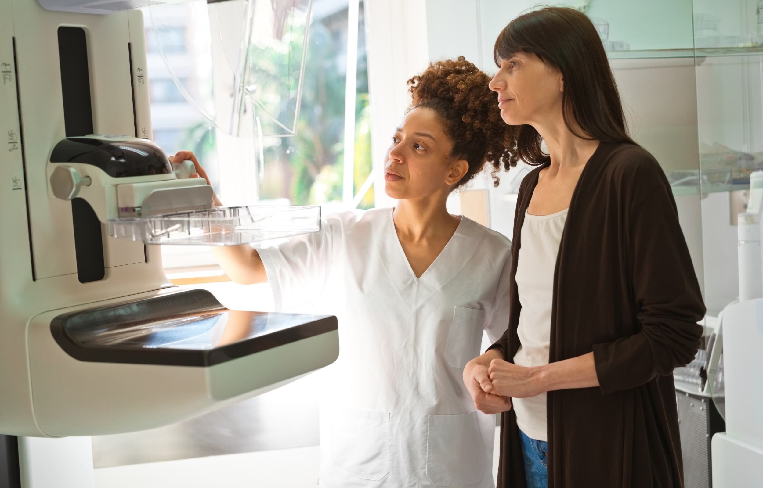A mammography technologist preparing a patient at a mammography machine