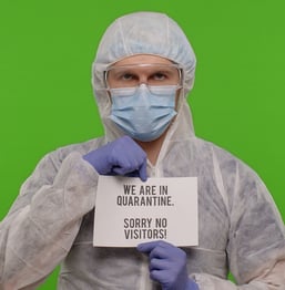 medical professional holding no visitors sign