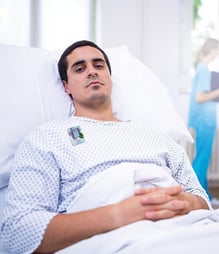 A patient in a hospital bed with a lavender Elequil Aromatab on his gown.