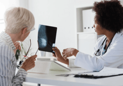 an older female patient looking at a mammogram image with her doctor