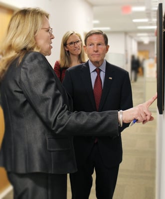 Senator Blumenthal touring Beekley Medical facility. Karin Copeland pointing to wall hangings that depict Beekley's history to Senator Blumenthal.