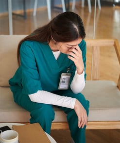 A nurse holding her head and burnt out