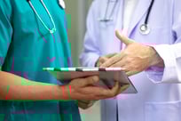 a medical technician and a doctor looking at a clipboard