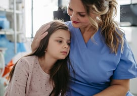 Anxious pediatric patient being held and comforted by a nurse