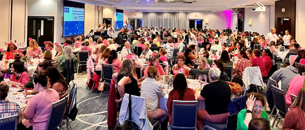 Designer Handbag Bingo - crowd of attendees seated at their tables; many in pink shirts