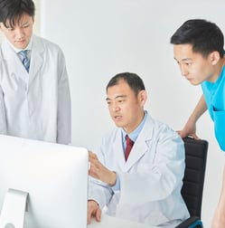 A radiologist reviewing a scan on a computer with peers.