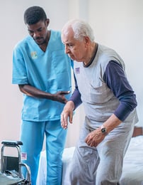 A nurse assisting an elderly patient, both of them wearing Elequil Aromatabs