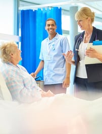 A patient speaking with a technologist and doctor in a hospital bed.