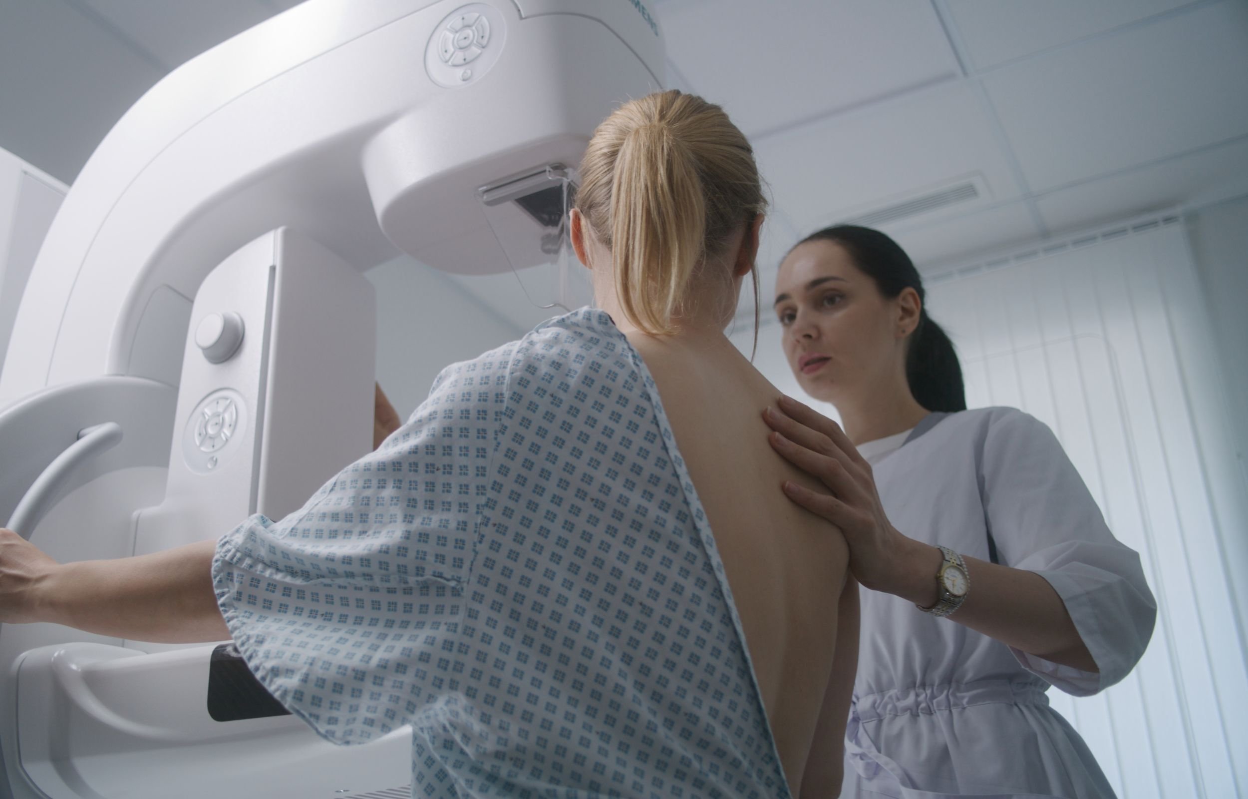 A mammography technologist lining up a patient at a machine.