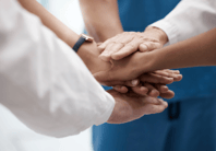five different hands from medical professionals on top of one another