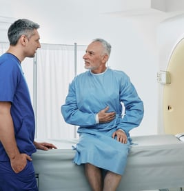 A patient talking to a technologist while holding his stomach.
