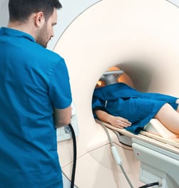 A technologist next to a machine with a patient in it.
