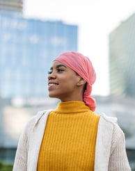 A woman smiling wearing a pink headwrap